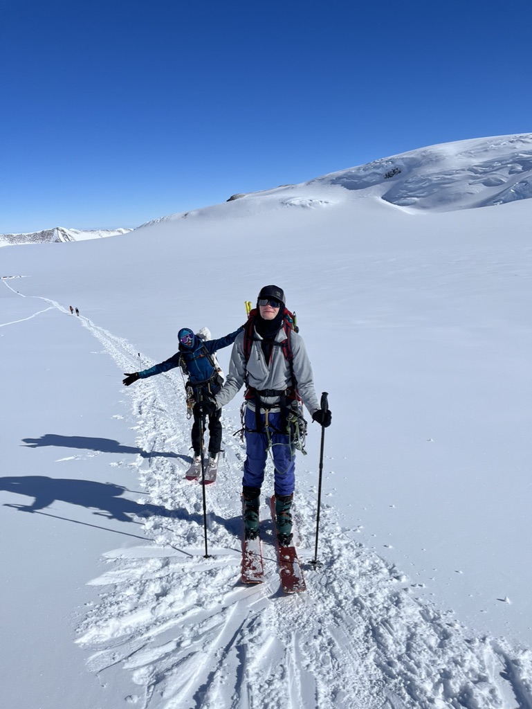 Ski tourers ascending glaciated terrain toward Svalbard summit with sea views