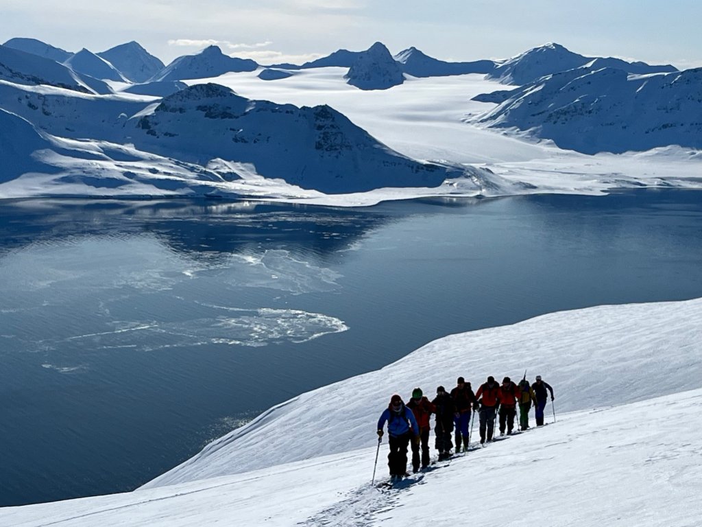 Group of skiers skinning above Arctic fjord on Sea-to-Ski Svalbard expedition, Svalbard Norway