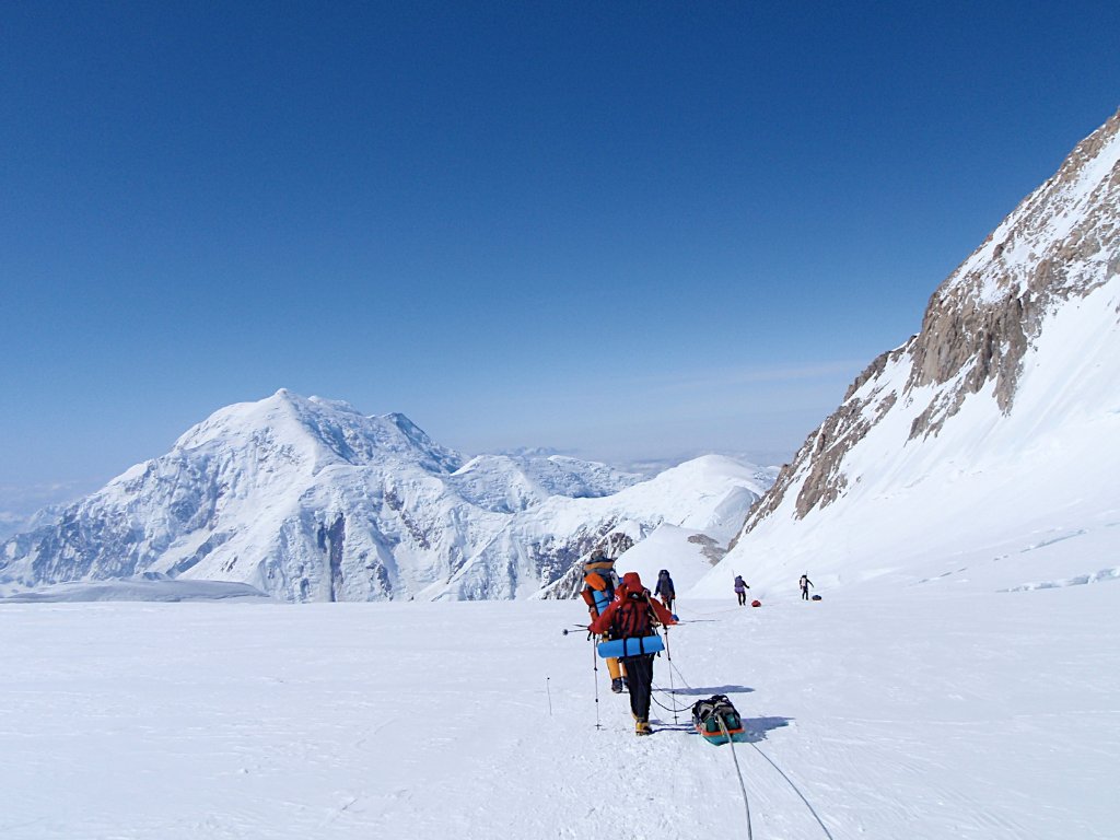 Group skinning up Svalbard ridge with frozen sea ice bay in background
