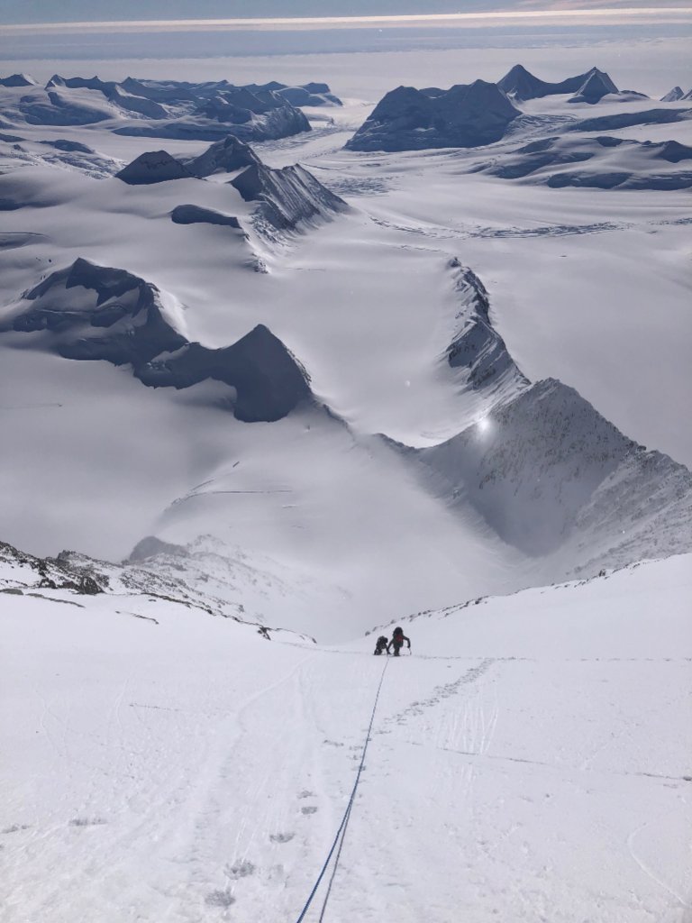 Ski mountaineers ascending steep couloir above Arctic sea in Svalbard, Norway