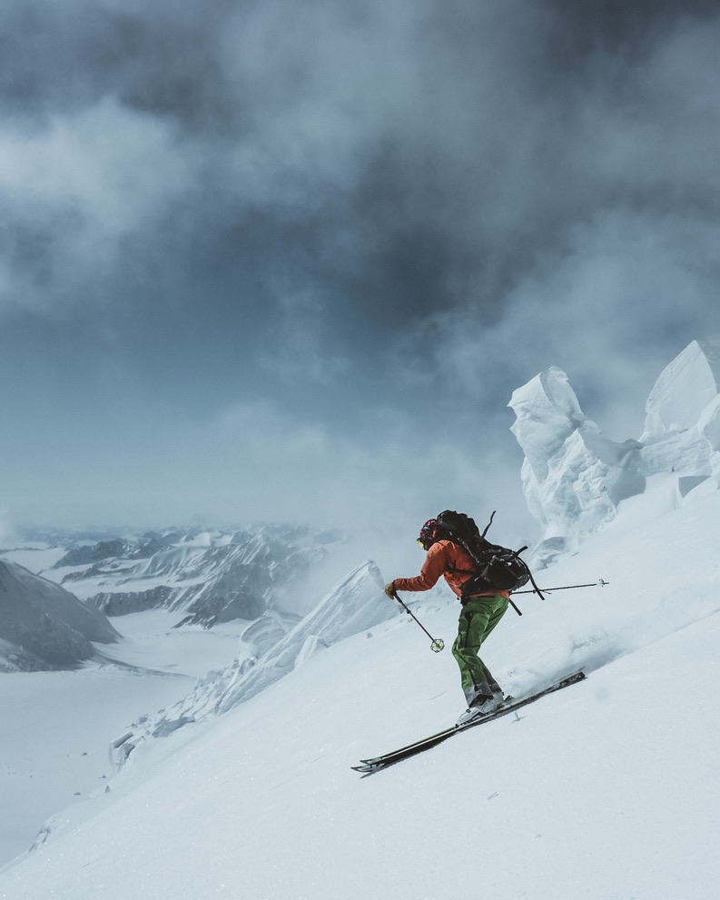 Sea-to-ski group skinning up Svalbard peak with icy fjord and glaciers below