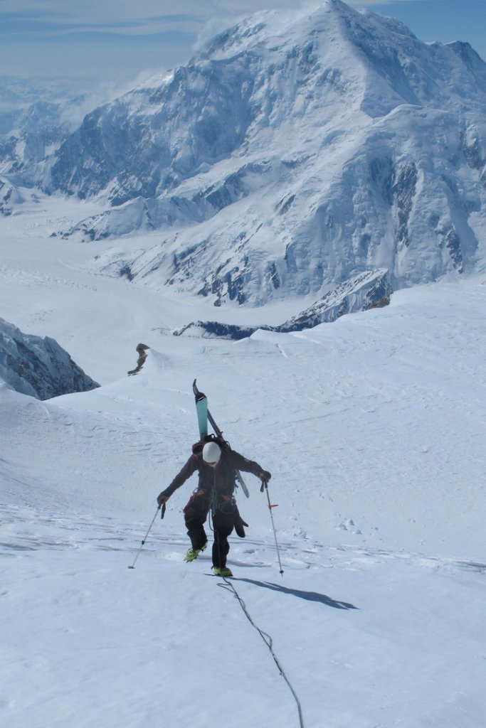 IFMGA guide bootpacking with skis on Svalbard summit ridge above ice-filled fjord