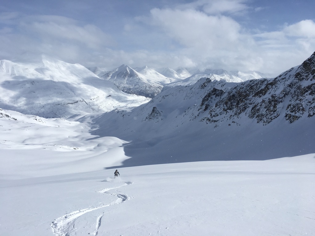 Ski mountaineers ascending steep couloir above Arctic sea in Svalbard, Norway