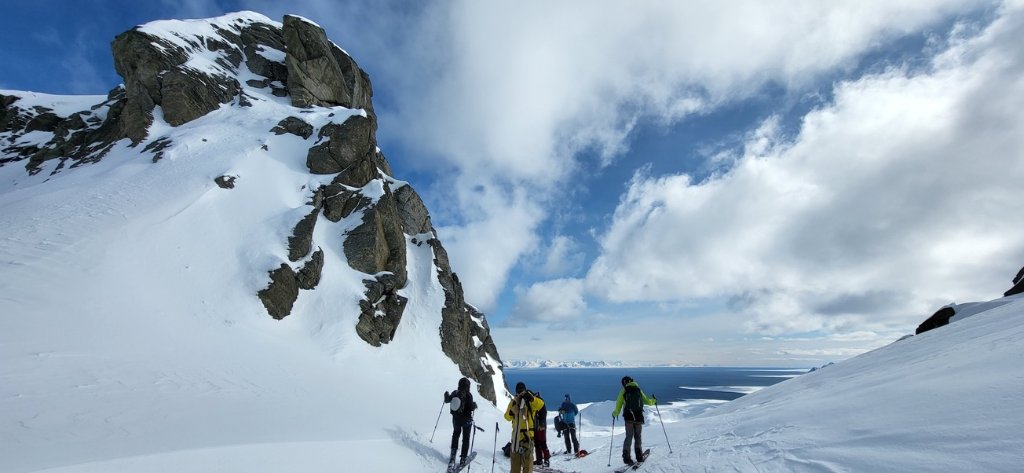 Ski touring group beneath dramatic rock spires in Svalbard Arctic wilderness