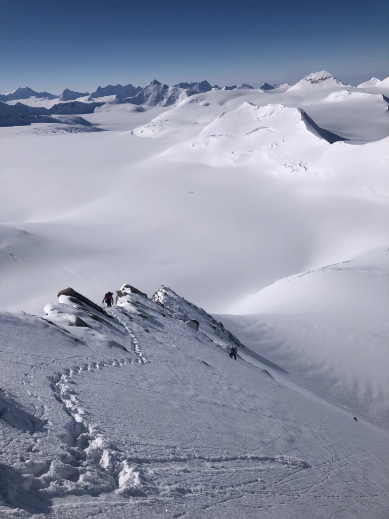 Guides and clients at remote Svalbard ridgeline above frozen Arctic fjord