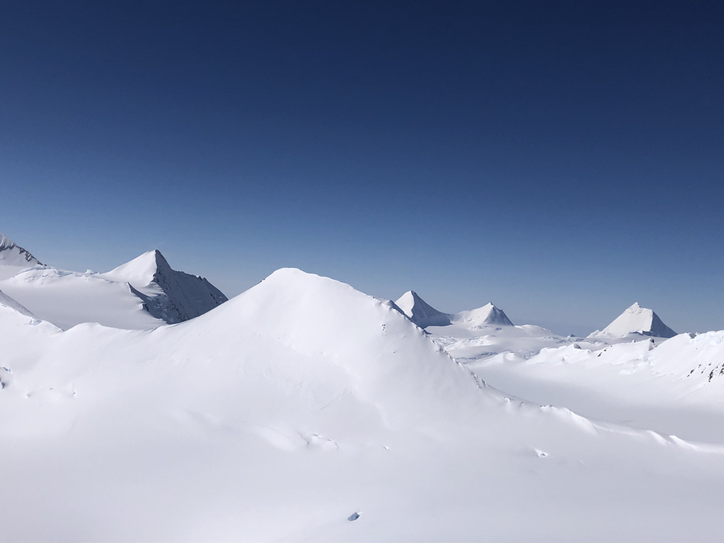Snow-covered alpine peaks under deep blue sky