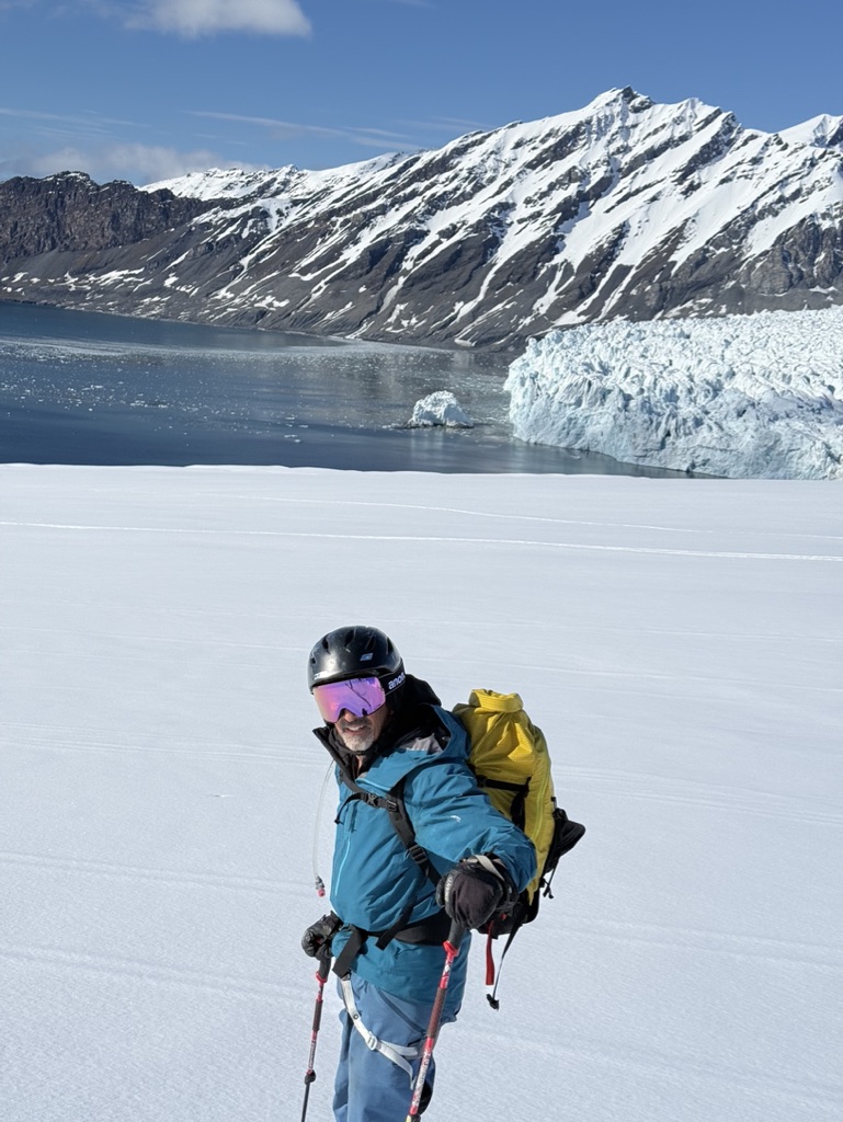 Skier on Arctic glacier with dramatic Svalbard peak and sea horizon