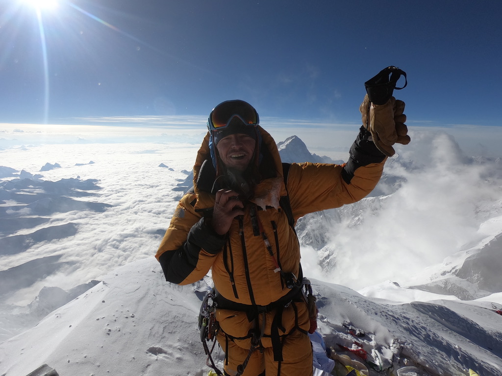 IFMGA guide bootpacking with skis on Svalbard summit ridge above ice-filled fjord