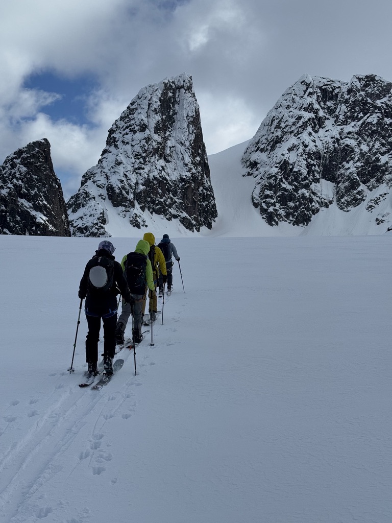 Ski tourers ascending glaciated terrain toward Svalbard summit with sea views