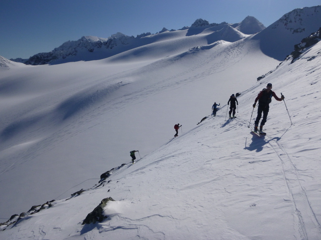 Ski mountaineers skinning up steep snow-covered slope in the Lyngen Alps, Norway