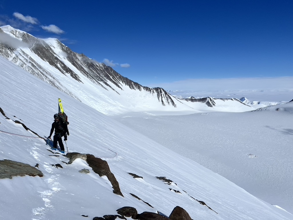 Skiers descending open snowfield above Arctic ocean in Svalbard