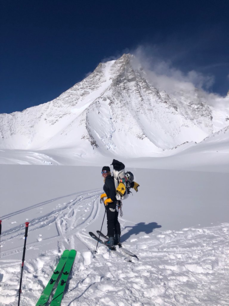 Sea-to-ski group skinning up Svalbard peak with icy fjord and glaciers below