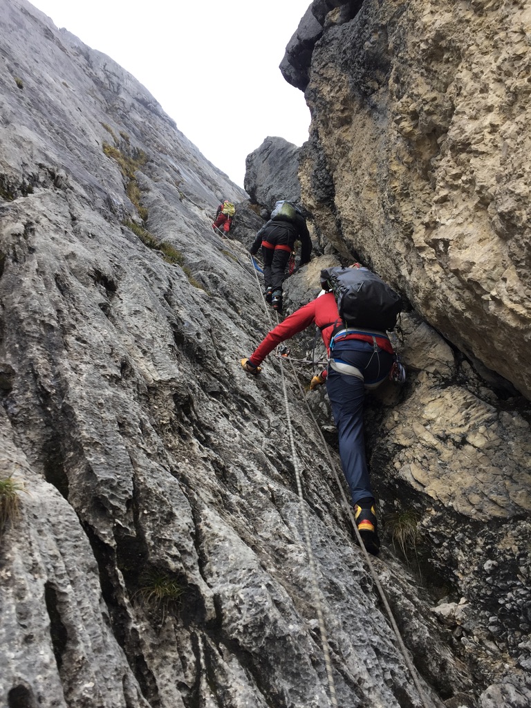 Ski mountaineers ascending steep couloir above Arctic sea in Svalbard, Norway