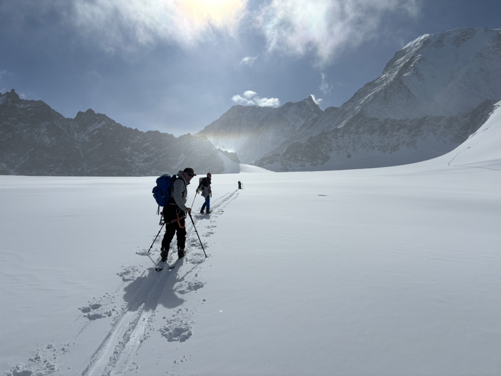 IFMGA guide bootpacking with skis on Svalbard summit ridge above ice-filled fjord