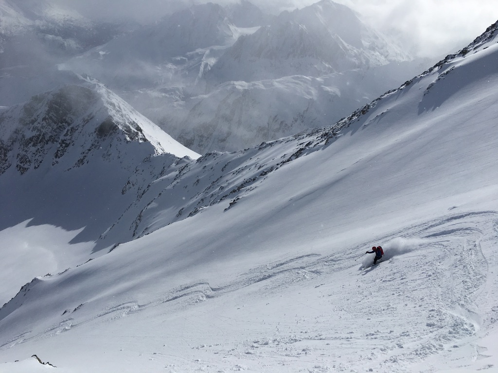 Ski touring party ascending Arctic slope above glaciated Svalbard fjord
