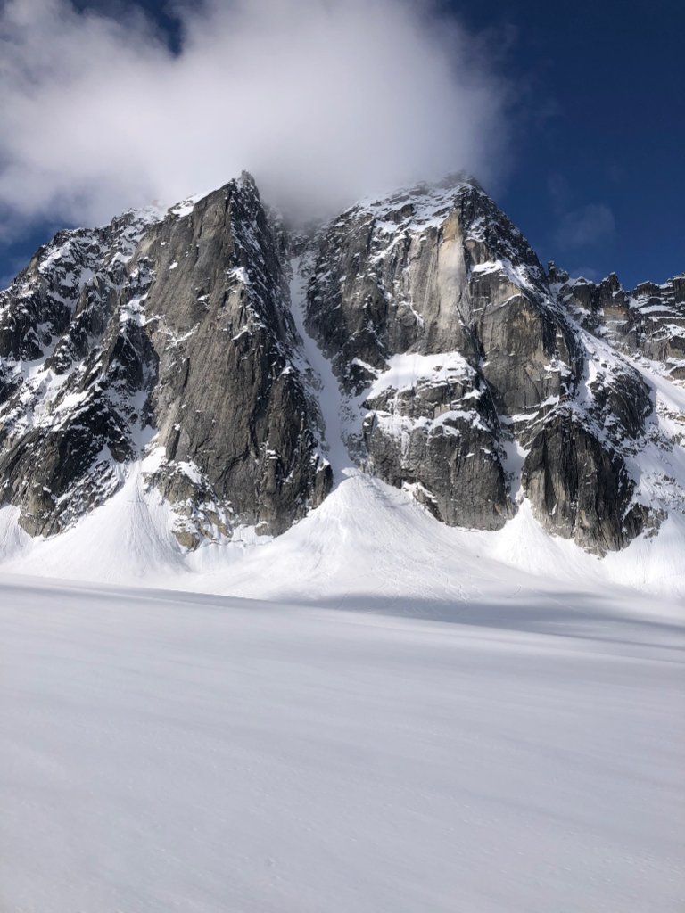 IFMGA guide bootpacking with skis on Svalbard summit ridge above ice-filled fjord