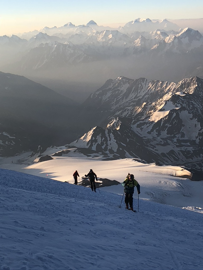 Skier making turns on corn snow with panoramic Arctic landscape, Svalbard