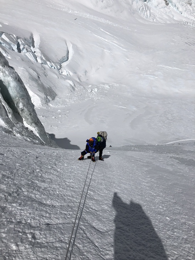 Sea-to-ski group skinning up Svalbard peak with icy fjord and glaciers below