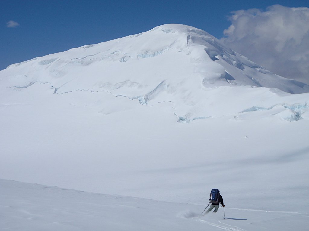 Sea-to-ski group skinning up Svalbard peak with icy fjord and glaciers below