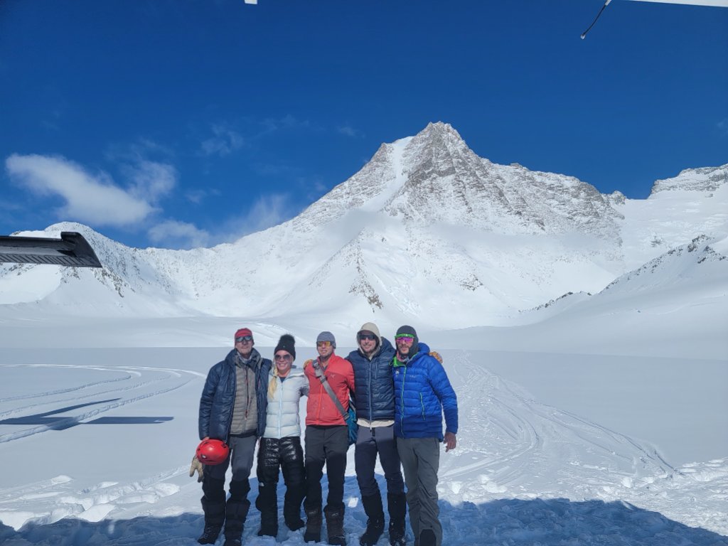 Ski tourers ascending glaciated terrain toward Svalbard summit with sea views