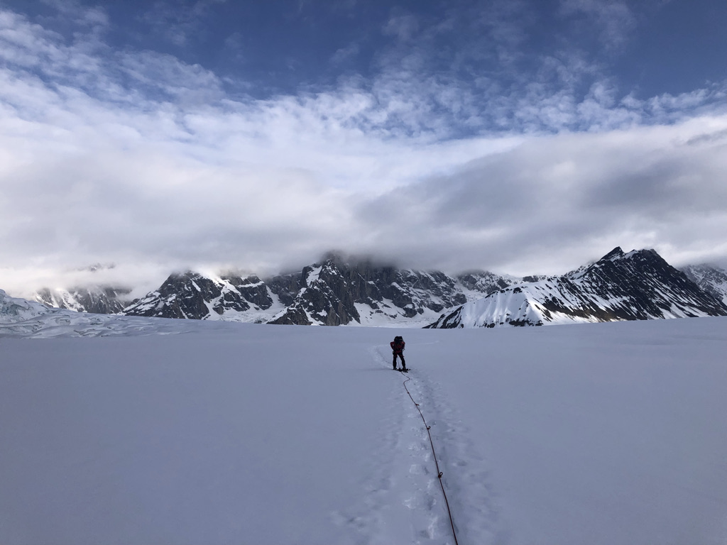 Climber on glacier with dramatic alpine peaks