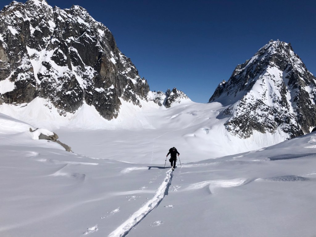 Ski mountaineers ascending steep couloir above Arctic sea in Svalbard, Norway