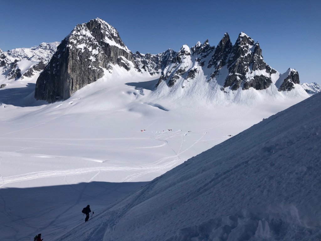 Ski tourers ascending glaciated terrain toward Svalbard summit with sea views