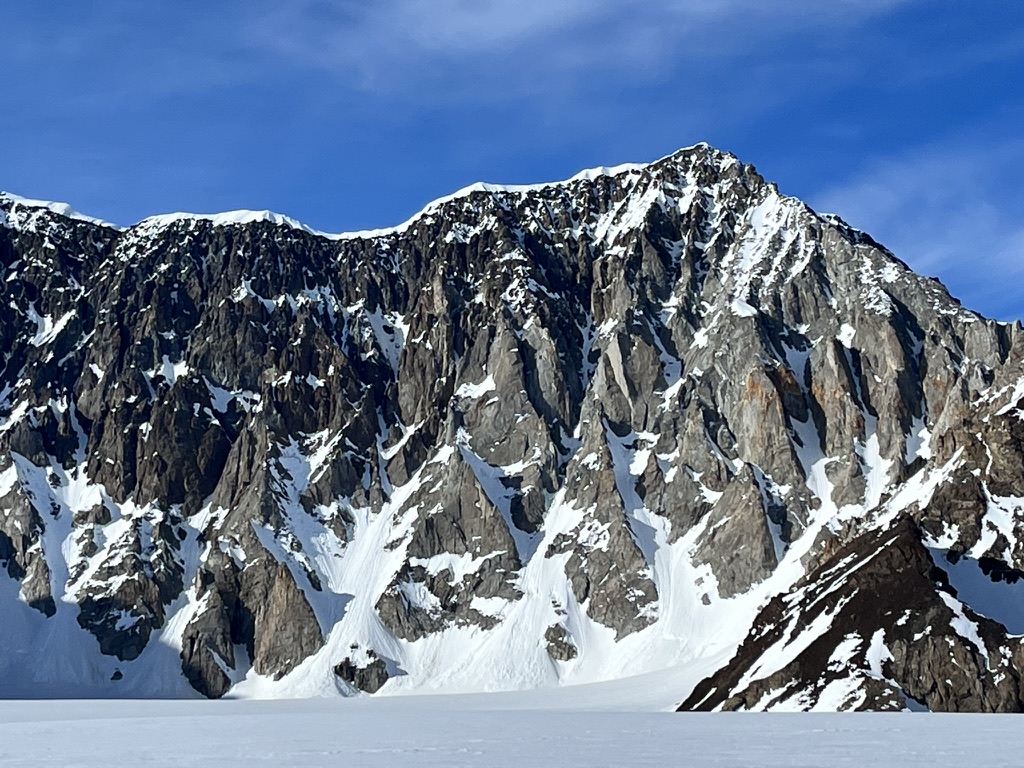 Ski mountaineers ascending steep couloir above Arctic sea in Svalbard, Norway
