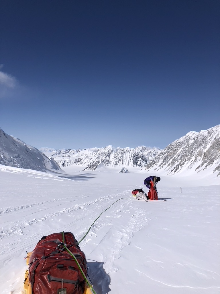 IFMGA guide bootpacking with skis on Svalbard summit ridge above ice-filled fjord