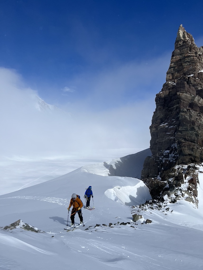 Ski touring group beneath dramatic rock spires in Svalbard Arctic wilderness
