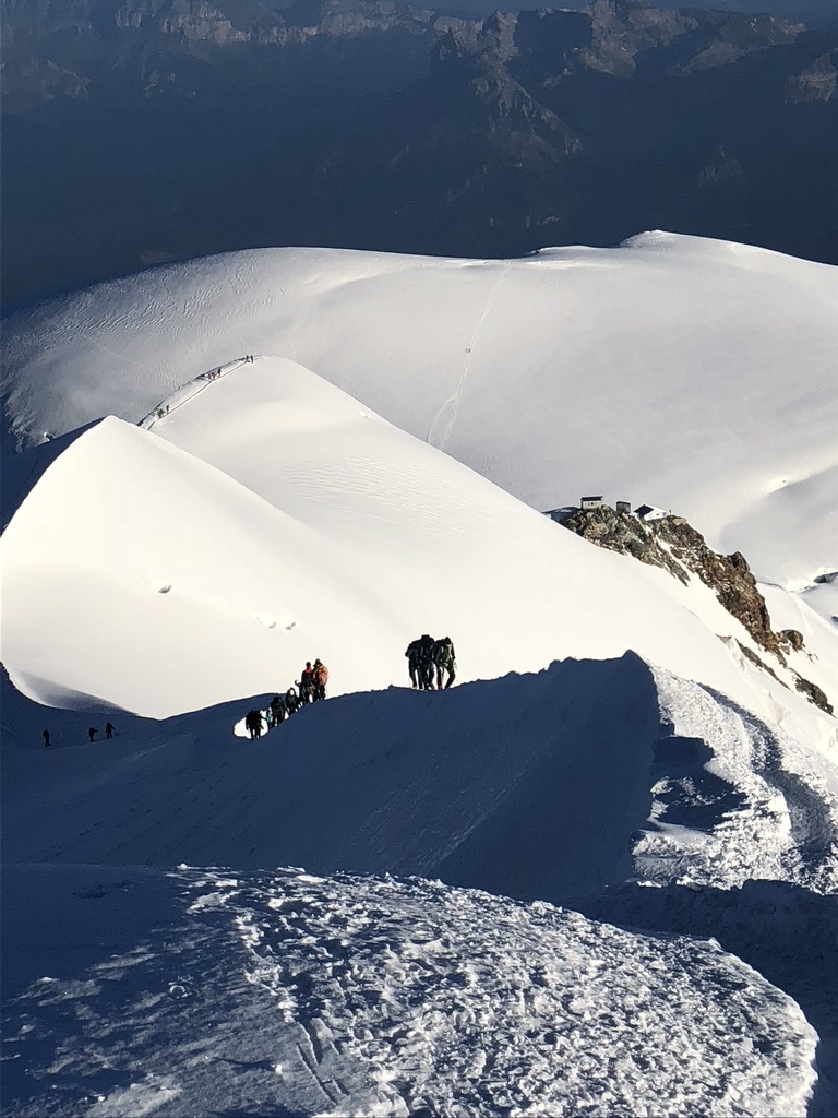 IFMGA guide bootpacking with skis on Svalbard summit ridge above ice-filled fjord