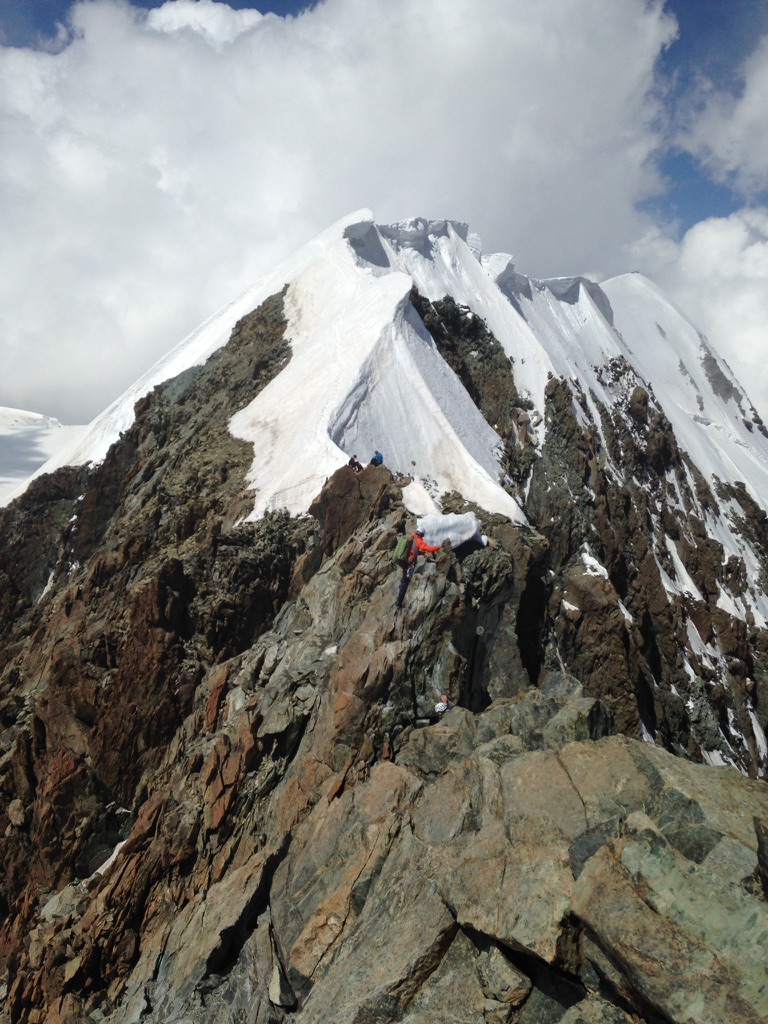 Ski mountaineers ascending steep couloir above Arctic sea in Svalbard, Norway