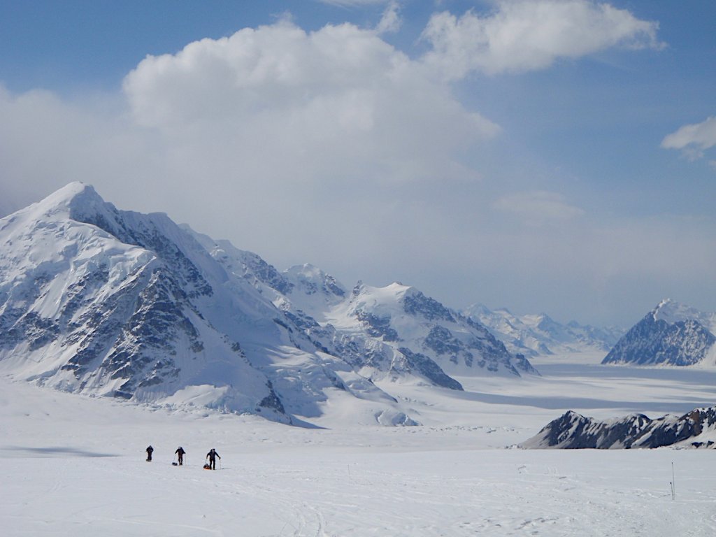 Ski touring party ascending Arctic slope above glaciated Svalbard fjord