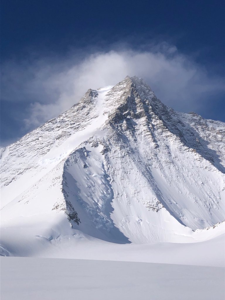 Skier making turns on corn snow with panoramic Arctic landscape, Svalbard