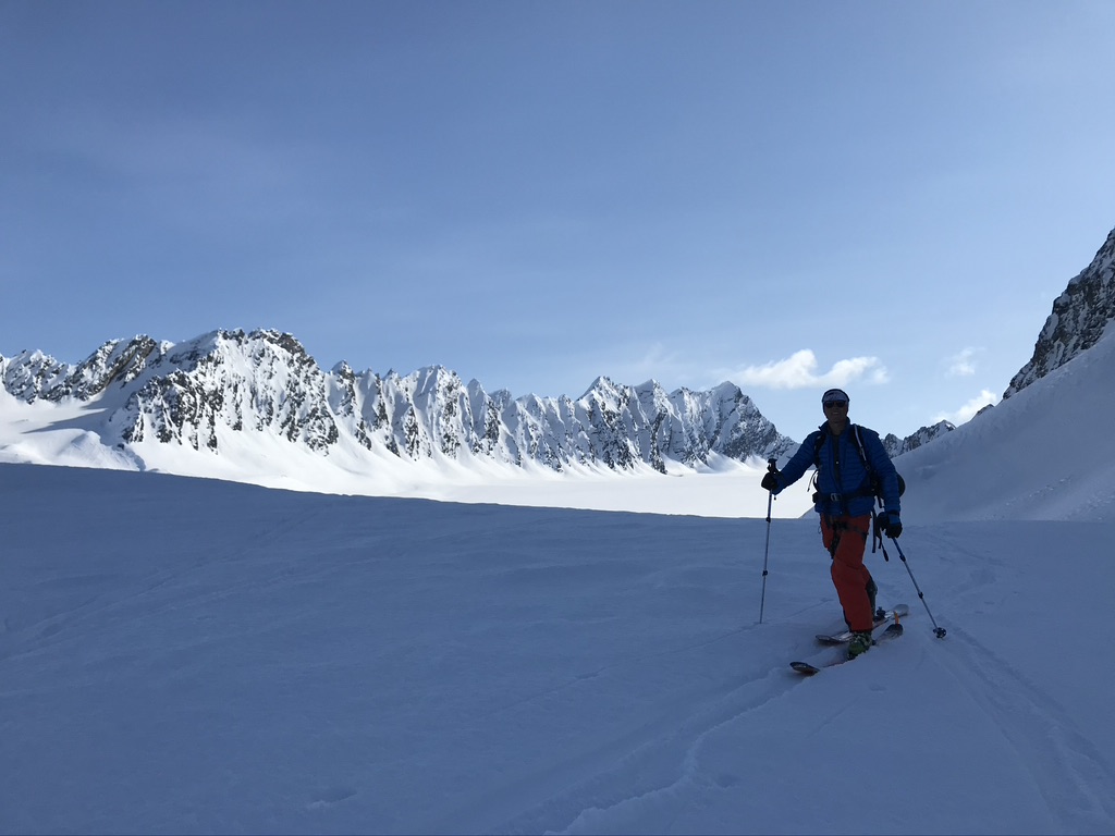 Skier making turns on corn snow with panoramic Arctic landscape, Svalbard