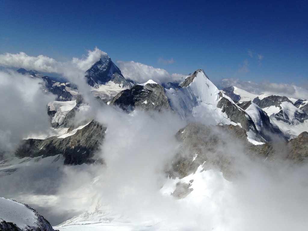Sea-to-ski group skinning up Svalbard peak with icy fjord and glaciers below