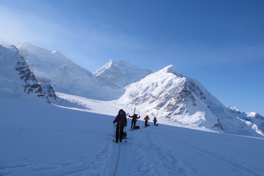 Ski tourers ascending glaciated terrain toward Svalbard summit with sea views
