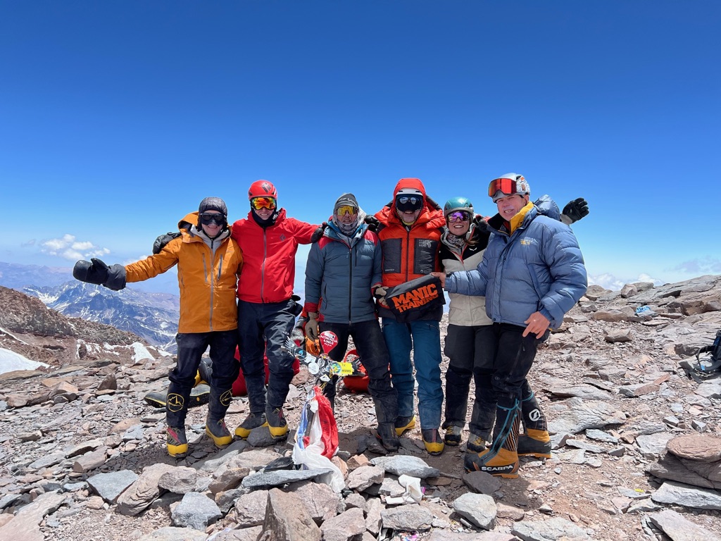Ski tourers ascending glaciated terrain toward Svalbard summit with sea views