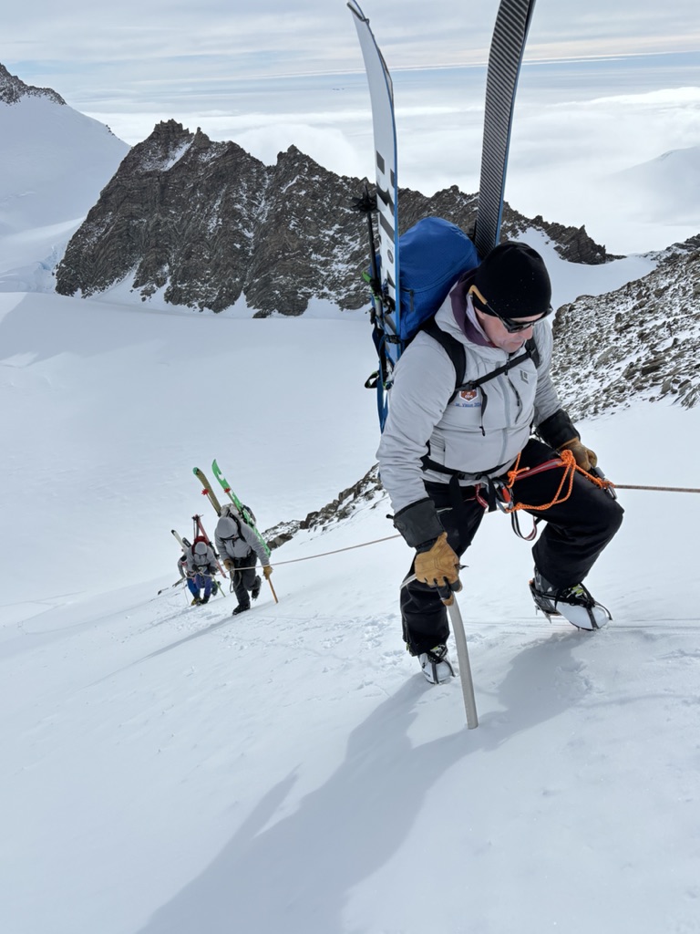 Ski mountaineers ascending steep couloir above Arctic sea in Svalbard, Norway