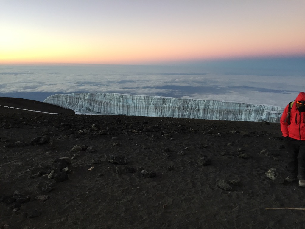 IFMGA guide bootpacking with skis on Svalbard summit ridge above ice-filled fjord