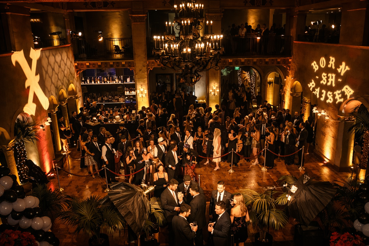 Luxury private party production at a historic venue — ambient uplighting, branded logo projections, red velvet stanchions, and a crowded gala floor with mezzanine overlooking the event. Live Pros AV event production in Los Angeles.