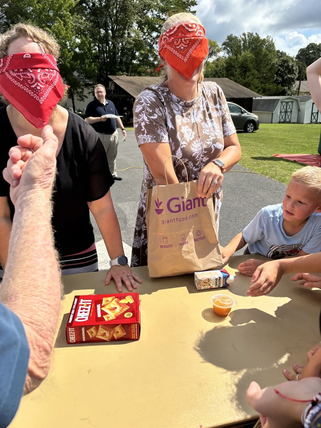 Two blindfolded women race through grocery bags at the game table