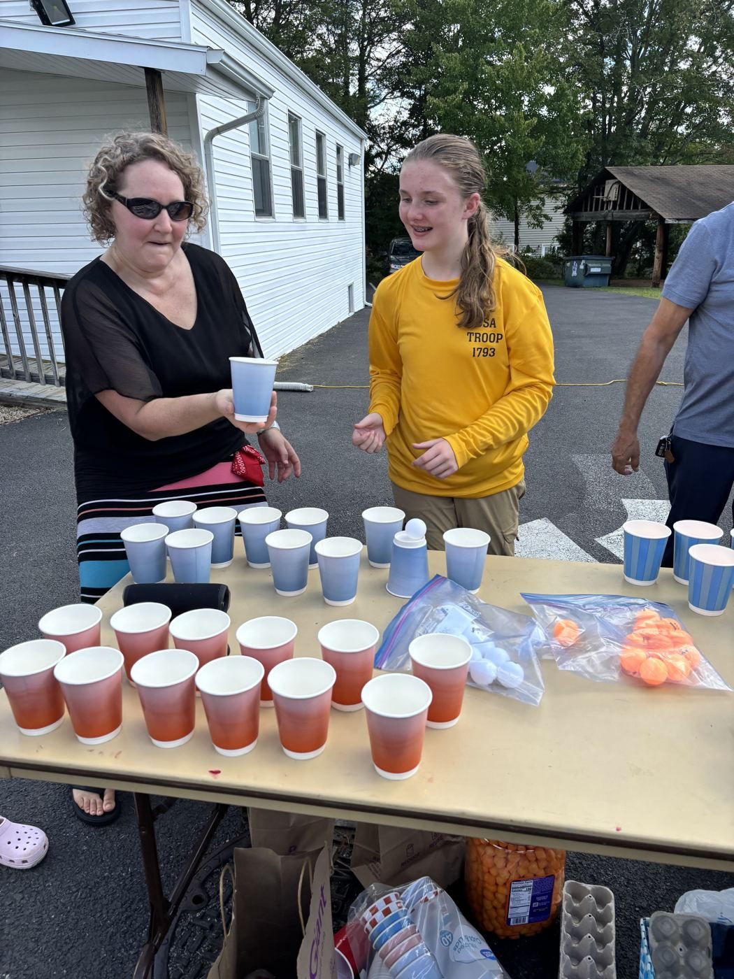 Volunteers laugh at the cup-and-ball game table