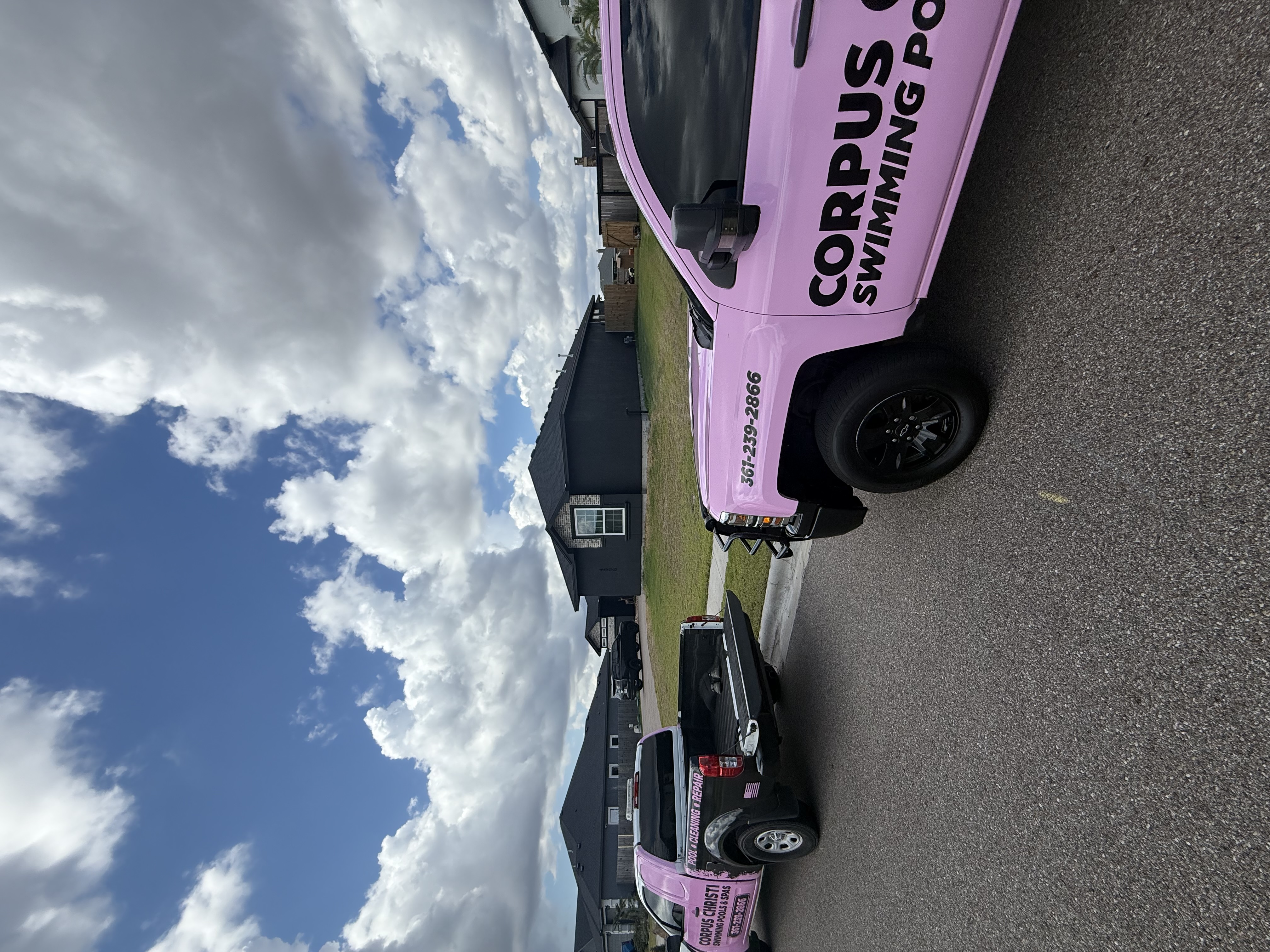 Two Corpus Christi Swimming Pools & Spas pink service trucks parked on a Corpus Christi street