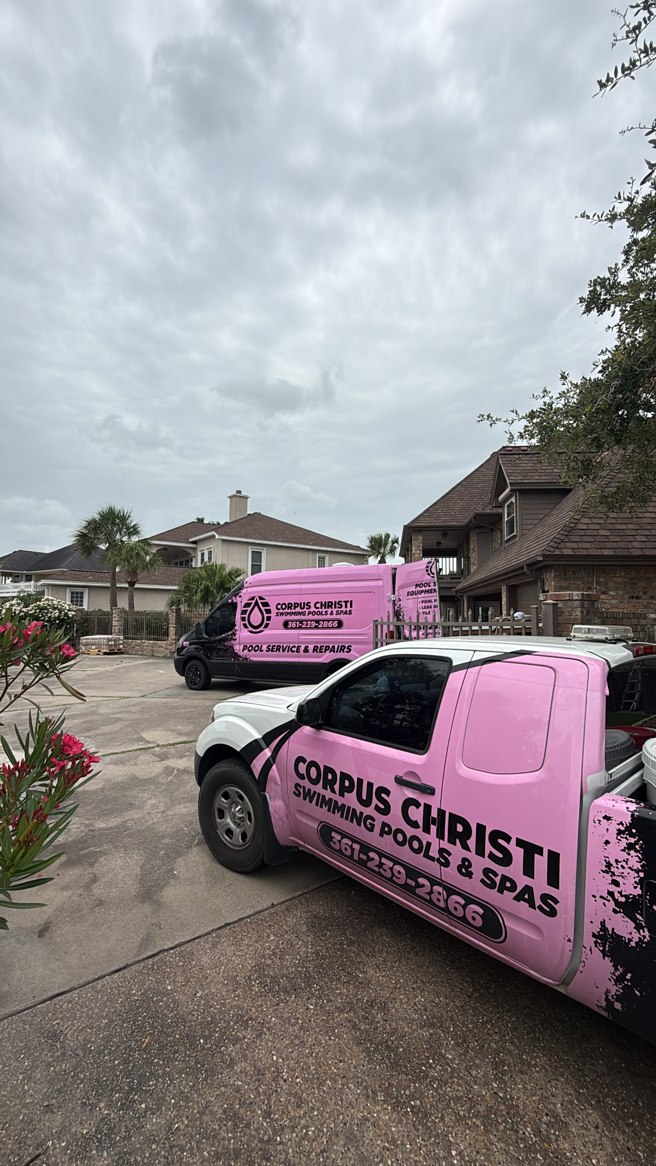 Corpus Christi Swimming Pools & Spas pink service truck and van parked in a residential driveway in Corpus Christi