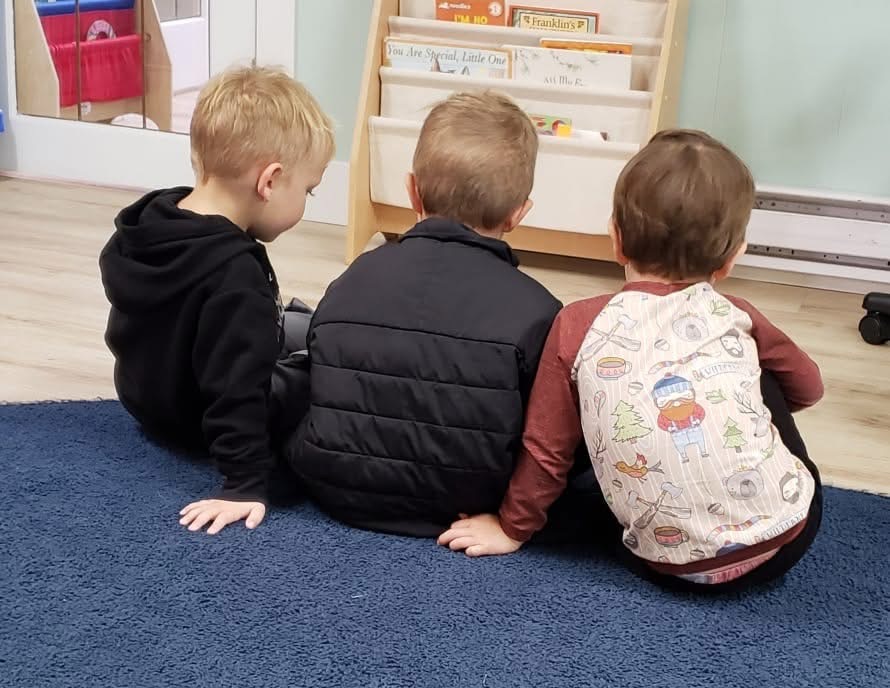 Three boys sitting together reading