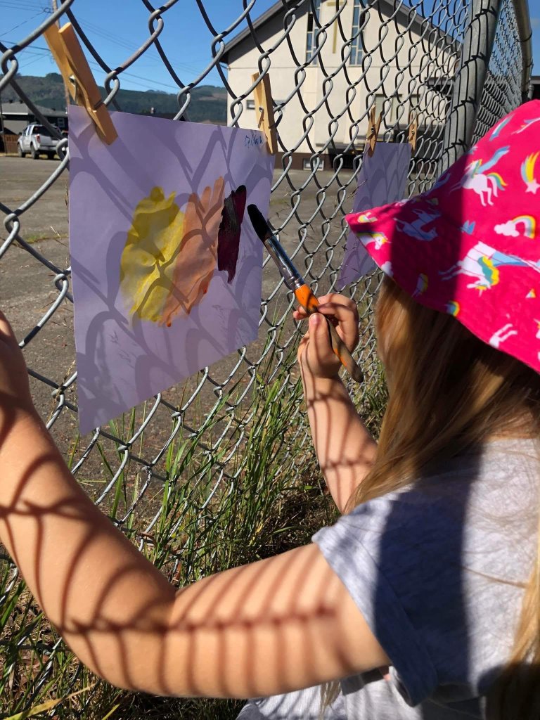 Child painting on canvas hung on the fence