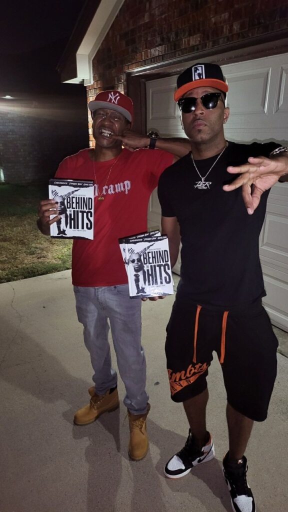 Malcom Watkins and Drumma Boy holding Behind the Hits book