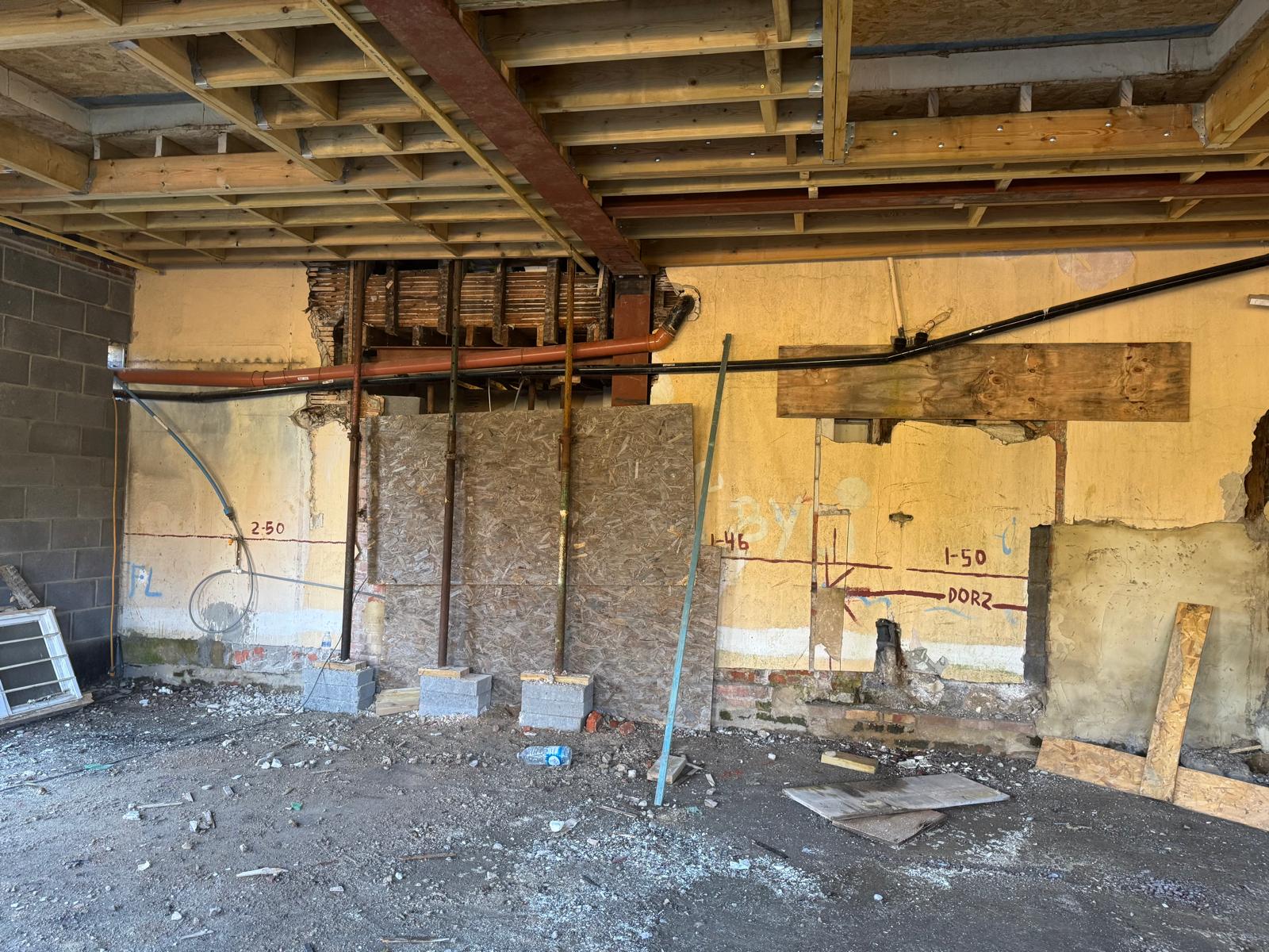Interior with exposed wooden beams and structural steel during construction