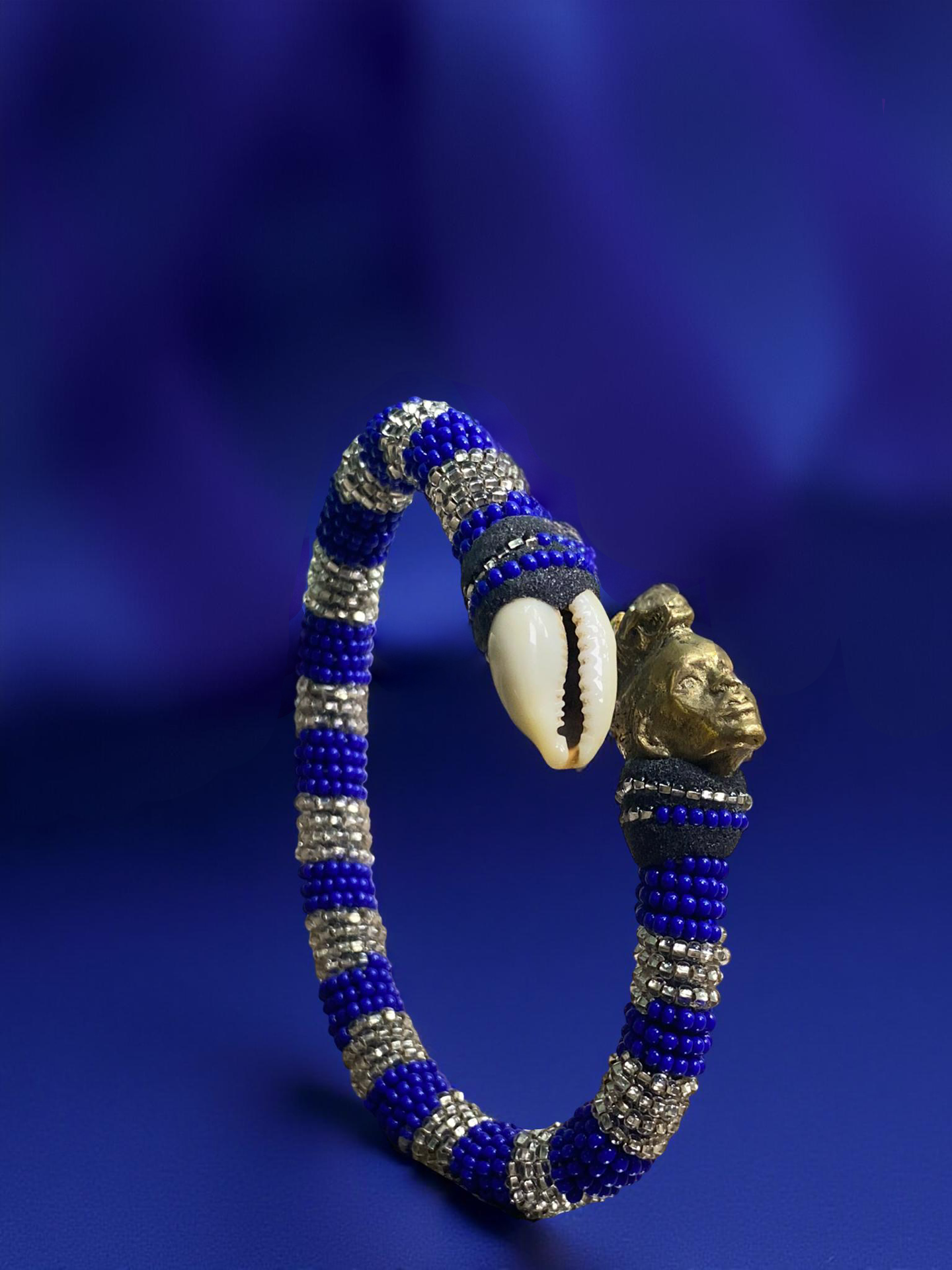 Royal blue and pewter beaded ildé with a cowrie shell and a bronze sculpted head